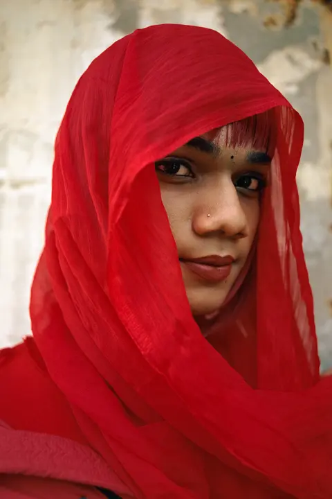 Une femme aux cheveux rouges portant un voile rouge assorti