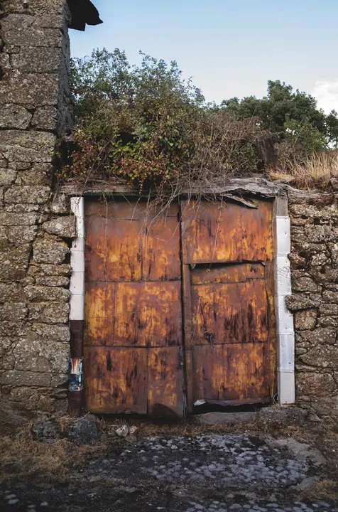 Weathered wooden doorway in an abandoned stone building in rural Spain, reflecting the depopulated landscape of España Vacía.