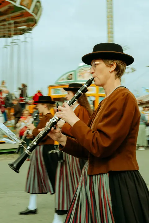 Traditional clarinet players in historic Bavarian costume performing at Munich Oktoberfest, celebrating folk music and cultural heritage at the festival.