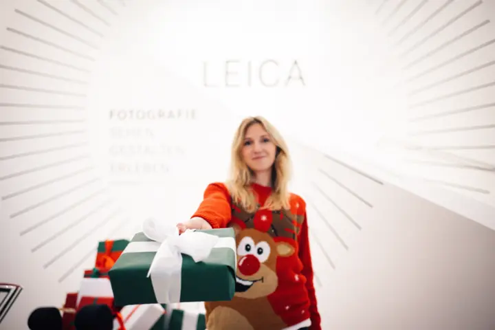 Young woman in a Christmas jumper holding a gift in front of her