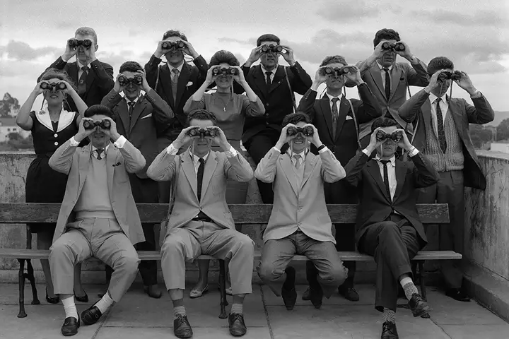 Women and men in 1960 with binoculars in front of their faces