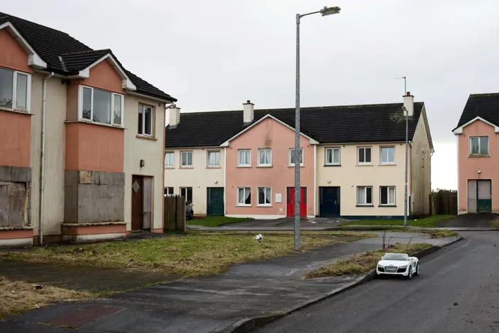 Photo of a run down estate with a toy car parked on the road.