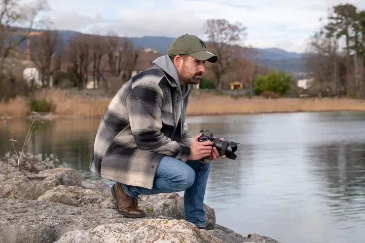 Cris Estalayo se penche avec son appareil photo devant un lac et regarde l'eau.