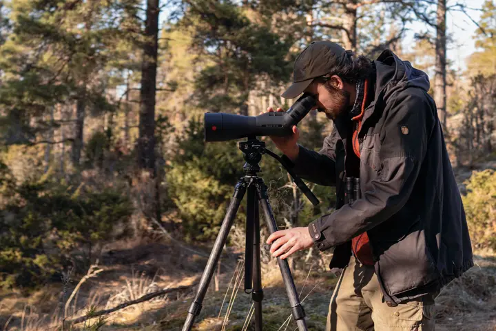 Ecologist Edwin using a Leica Televid HD spotting scope on tripod in Finnish woodland.