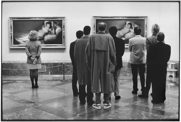 People looking at two paintings at an art exhibition