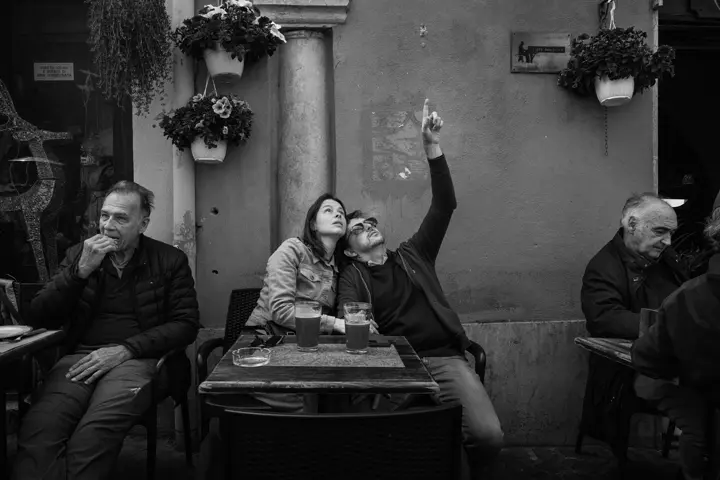 Black and white street photograph of two people sitting in a café