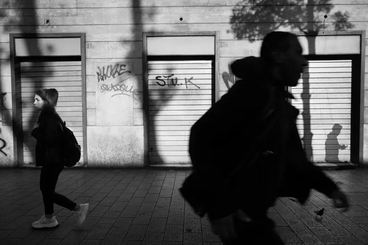 Black and white street photograph of two people walking through the streets