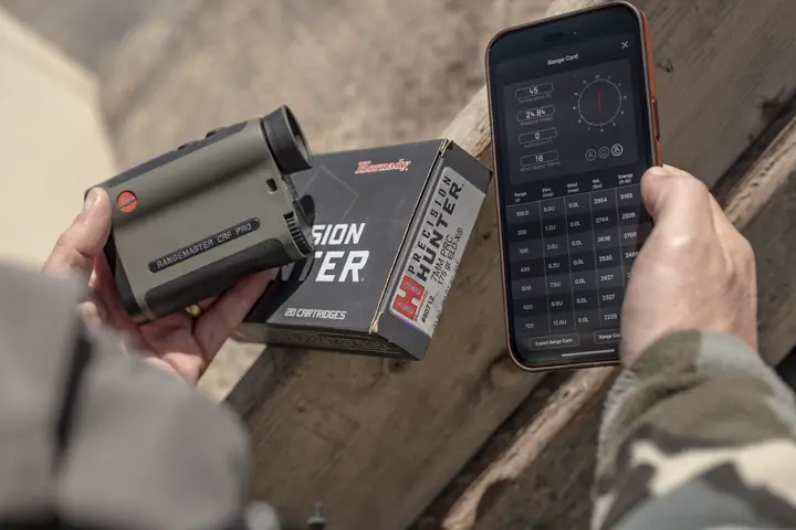 A hunter is holding his Leica CRF Rangemaster and his smartphone