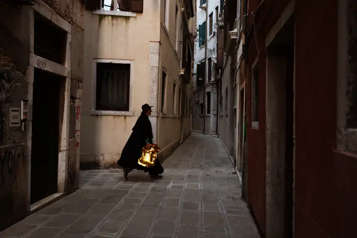 Man with golden mask in hand in the alleys of Venice