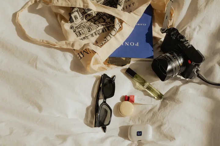 Leica Q3 with other items e.g. a sunglasses and headphones on a bed