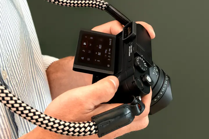 Man holding his leica Q3 Monochrom camera with the display folded out in his hand