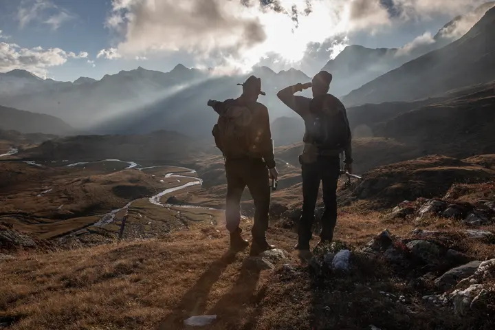 Two men stand, observing the vast landscape
