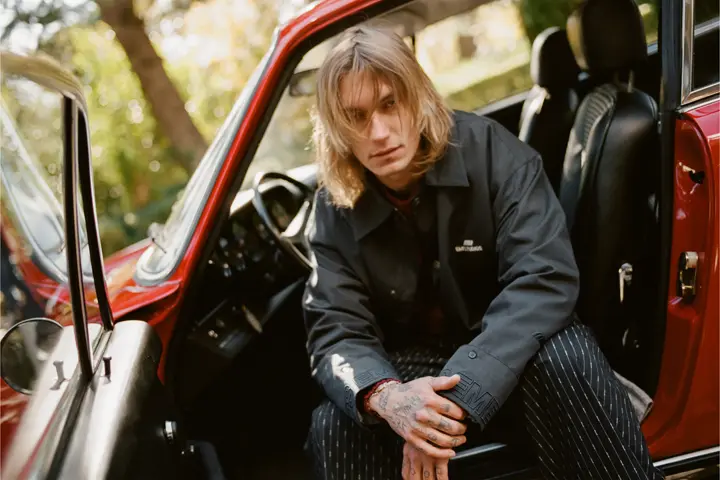 Chico sentado en un coche con la puerta abierta