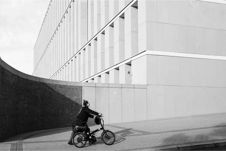 Persona llevando bicicleta con edificio blanco de fondo