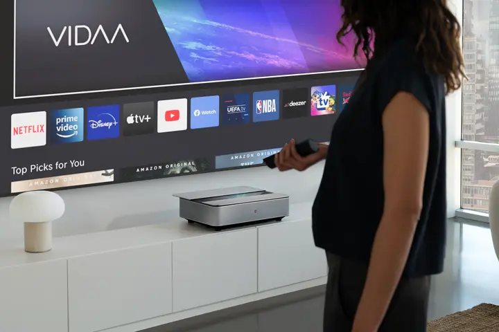 Woman in front of a Leica Cine 1 projection holding the remote control in her hand.