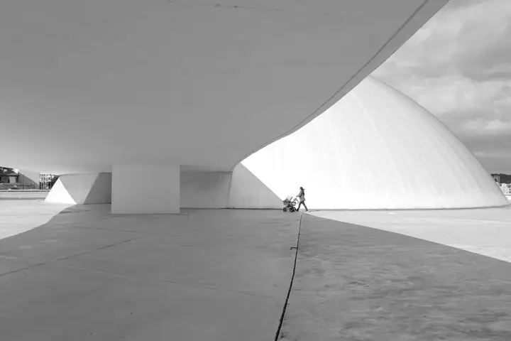 Gente paseando con carrito de bebé debajo de un puente