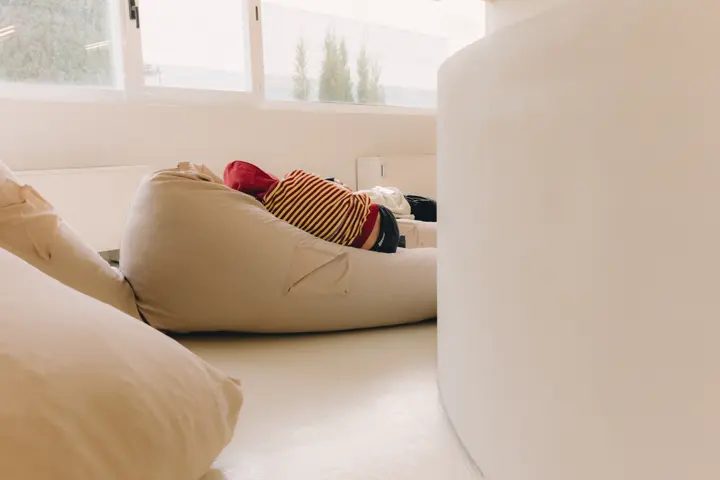 Persona tumbada en sillones de una oficina en su descanso