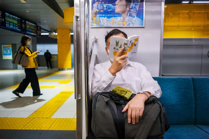 man sitting reading in a underground train