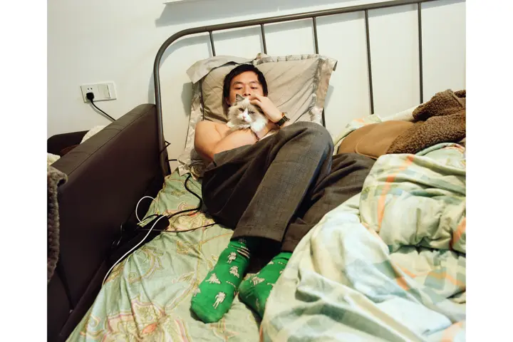 Man in a bed hugging a cat