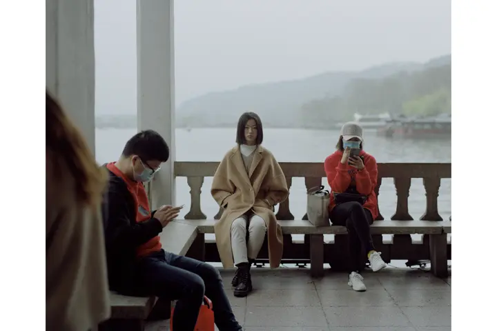 People sitting down in a bench with water behind