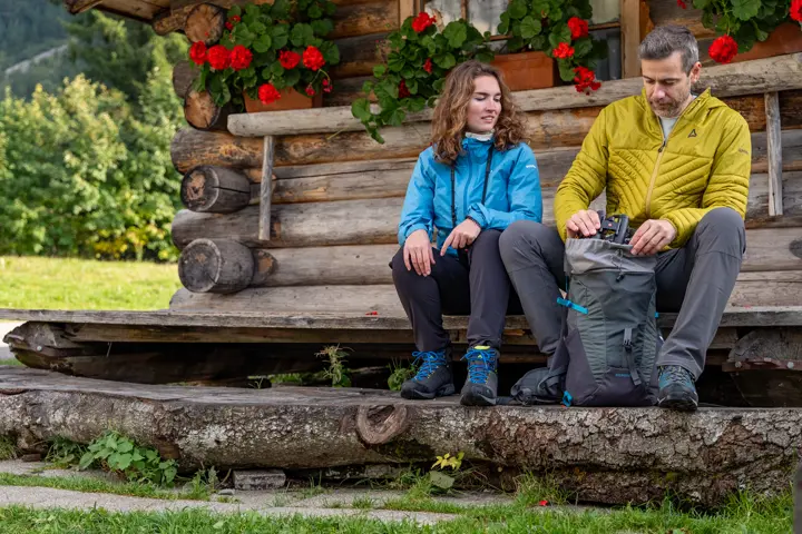 Two hikers resting in front of a cabin