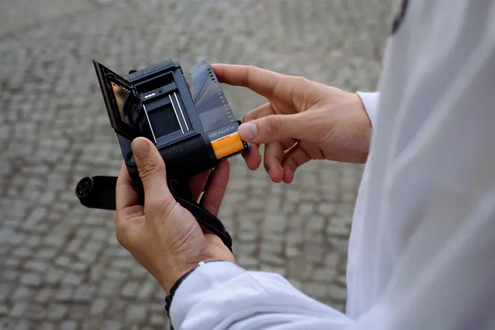 A person is loading film into the Leica M6.