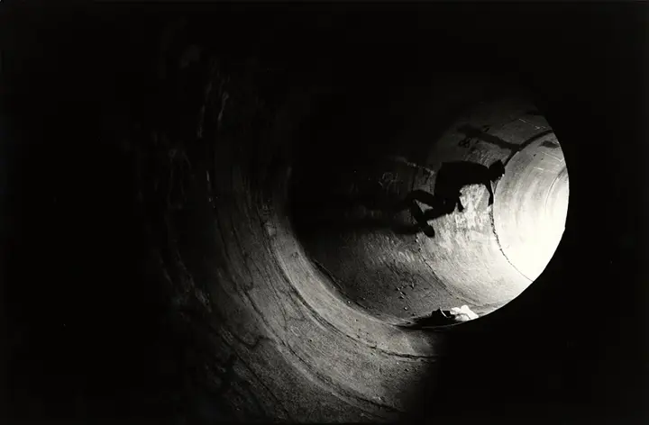 Skateboarder driving through tunnel b&w