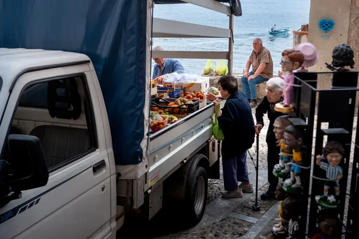 A photograph of people standing next to a fruit seller van.