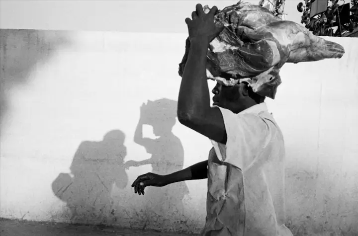 black man carrying something on his head b&w