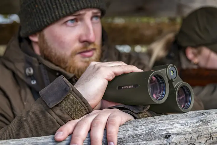 Hunter on a high seat using his Leica Geovid Pro in olive green