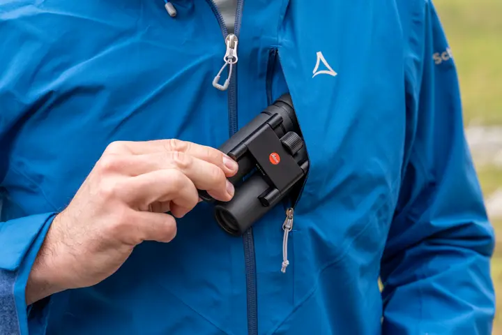 Man is pulling his Leica Noctivid Compact out of his pocket