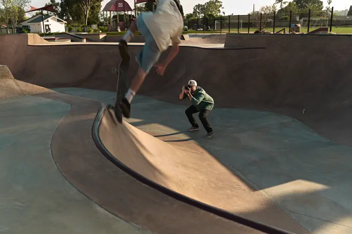 Jaime is taking a photo of a boy on his skateboard in the skate pool