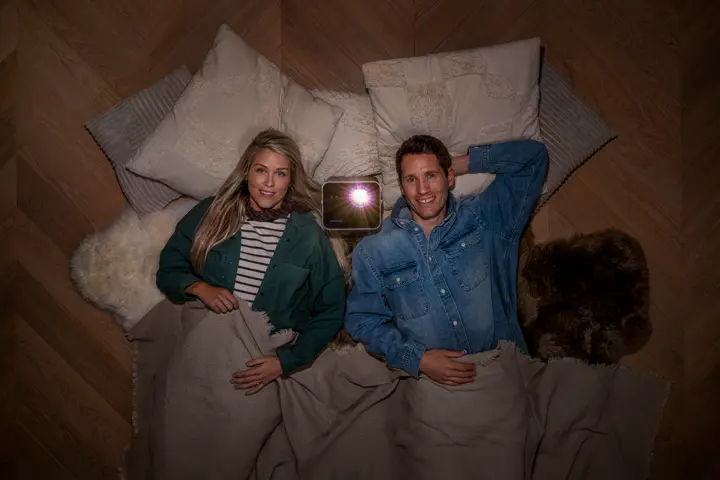 A couple are lying on the floor looking up at the ceiling, with the Leica Cine Compact 1 in the middle