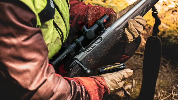 hunter-loading-ammunition-into-rifle-with-leica-scope-during-outdoor-hunting-experience