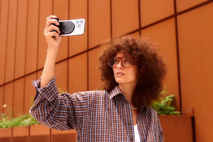 Woman with curly hair using the Leica LUX Grip with her iPhone