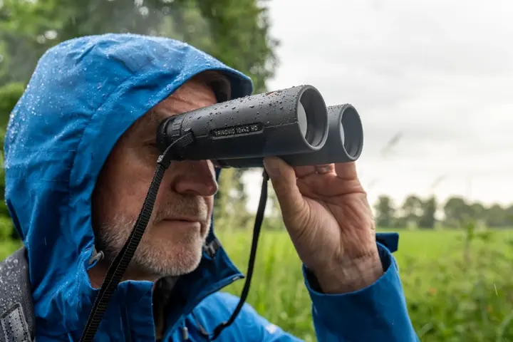 Man is looking through his trinovid HD in the rain