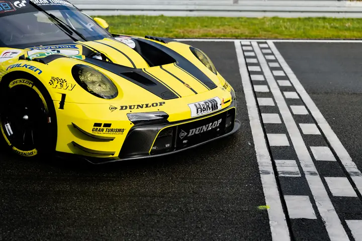 Close-up of a GT race car on a wet circuit, highlighting aerodynamic design, performance engineering, and motorsport detail.