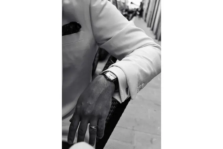 Brazo de un hombre con un traje blanco y un reloj en la muñeca