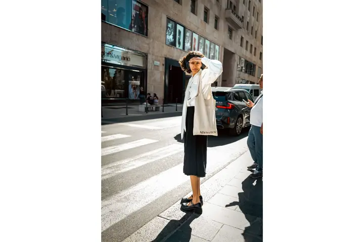 Mujer esperando para cruzar un paso de peatones mirando con la mano de parasol