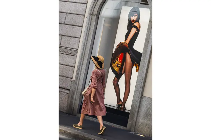 Mujer caminando por una ciudad pasando al lado de un escaparate con la foto de otra mujer