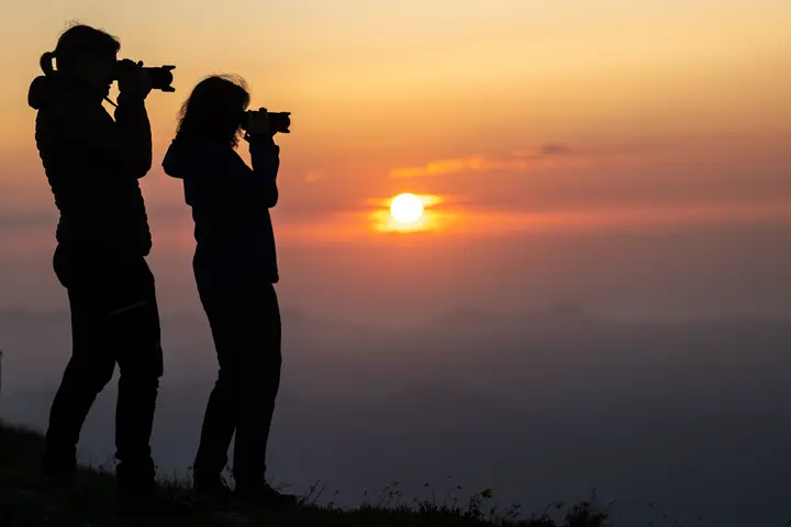 Photographers capturing sunrise from a mountain ridge.