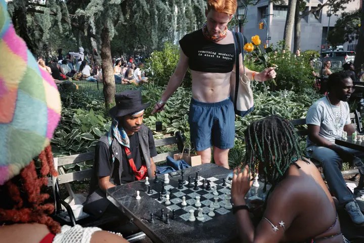 People playing chess while others gather in a busy public park.