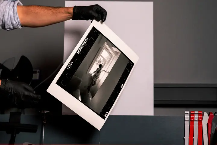 Gloved hands holding a Leica MONOPAN 50 photographic print.