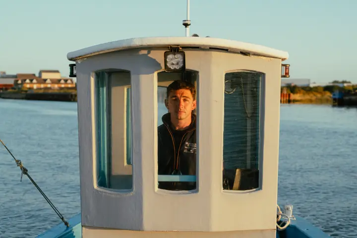 A man in the wheelhouse of a fishing boat