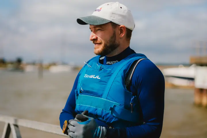 Portrait of a man wearing a blue life jacket by the sea