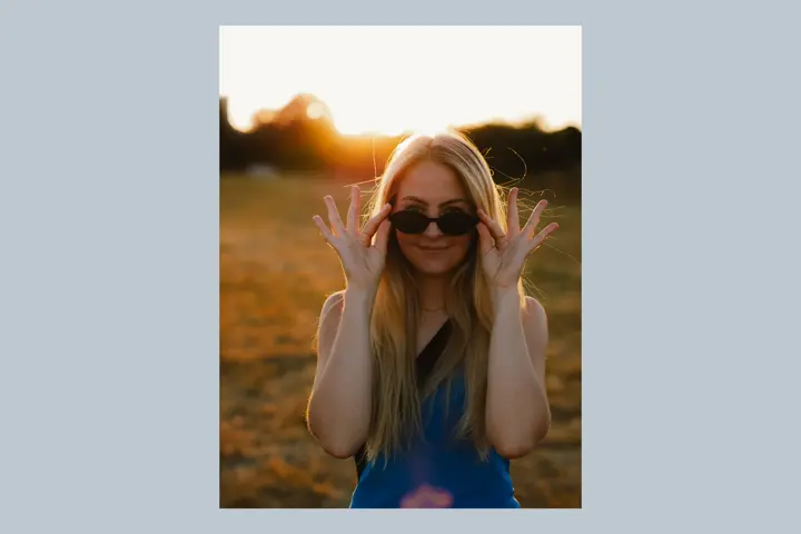 Portrait of a young blonde woman wearing a sunglasses in the sunset