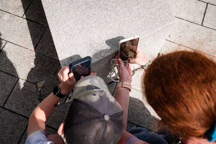Two people comparing photos on their smartphones outdoors.