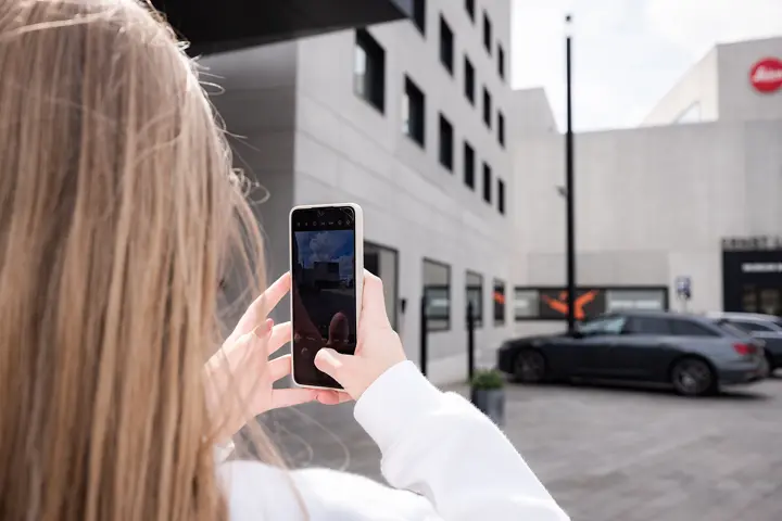 Person photographing the Leica Campus with a smartphone.