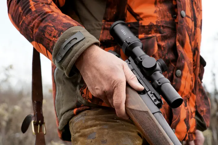 Close-up–of–a–hunter–holding–a–Leica–Fortis–and–wearing–orange–camouflage