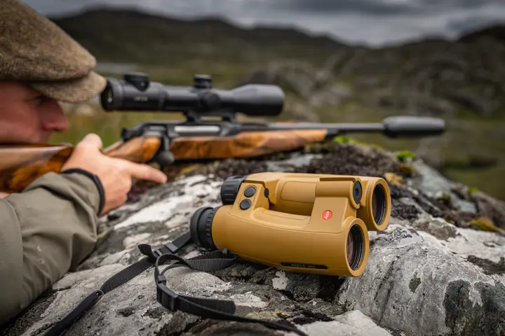 Hunter aiming with his rifle and the Geovid Max is next to him